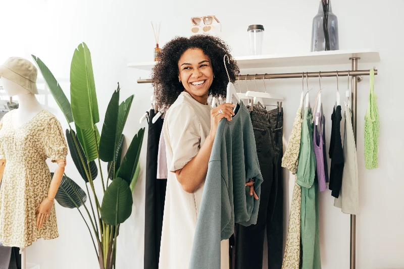Laughing woman customer choosing sweatshirt in a store